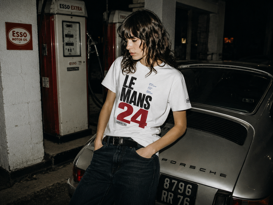 MONORETRO Le Mans 24 T-shirt in white, worn beside a classic Porsche 911 at a vintage Esso filling station.