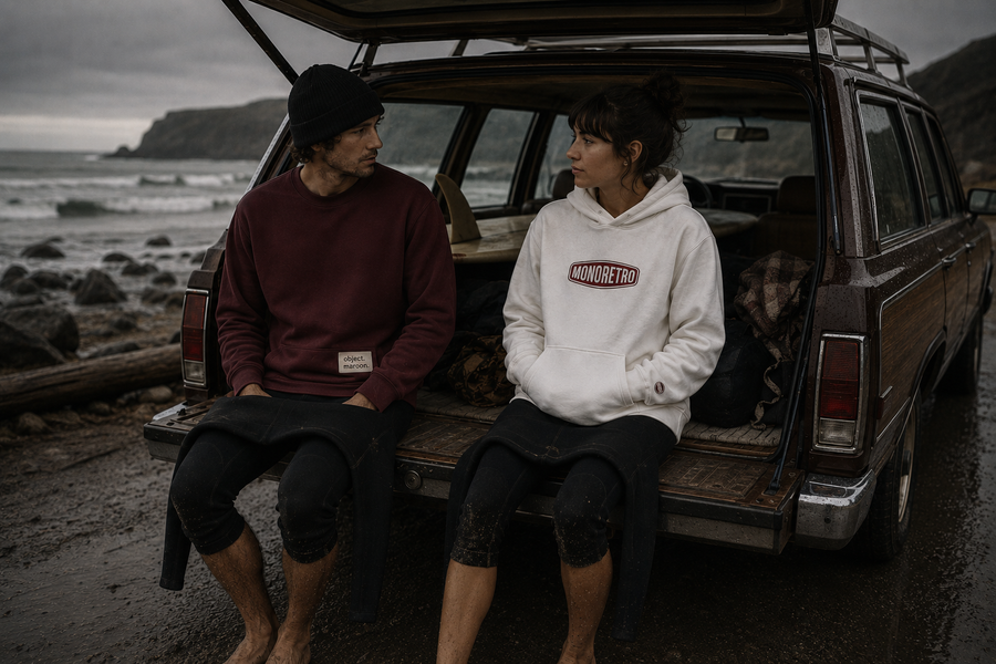MONORETRO sweatshirt in burgundy and hoodie in white, worn in the back of an estate car at the coast.