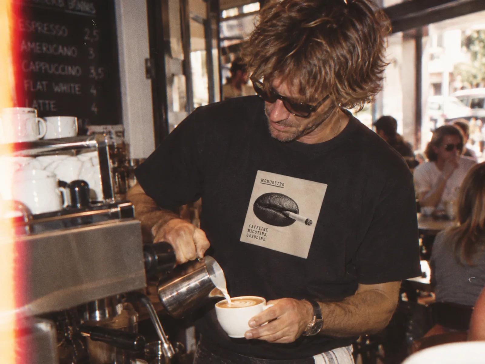 A barista pouring a flat white behind the counter